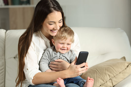 Mother and baby playing with a smartphone on a couch
