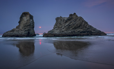 Sea stacks reflected in the water at sunset on a beach in Bandon, Oregon