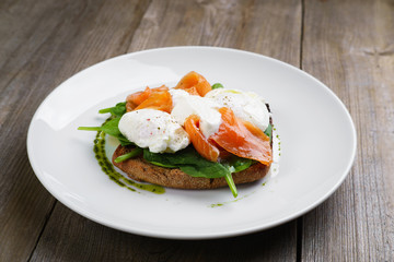 Wholemeal bread toast and poached egg with smoked salmon and spinach, healthy breakfast, restaurant menu photo, diet food