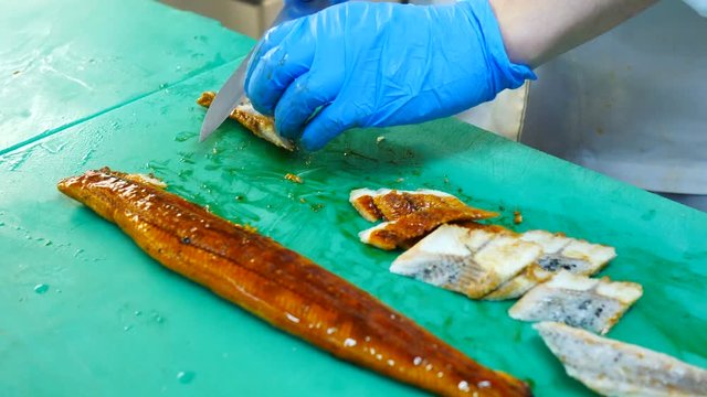 Marinated acne in soy sauce, chef cuts fish for sushi, close-up, macro video