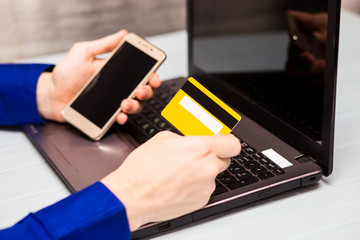 Man hold credit card  in hand and entering security code using laptop keyboard at home. Technology, banking, home, lifestyle and online shopping conceptconcept