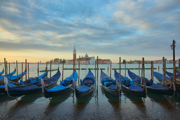 Fototapeta na wymiar Gondolas in front of the San Giorgio Maggiore church in Venice at sunrise
