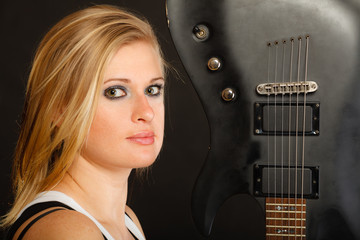 Blonde woman holding electric guitar, black background