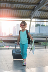 Child with suitcase and city map on summer vacation. Travel and adventure concept.