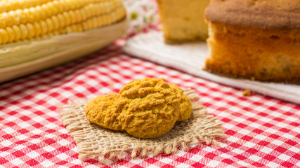 Delicious yellow cookie of corn. Sweet food of Festa Junina, a typical brazilian party. Red plaid fabric on table.
