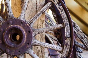 Old wooden wagon wheel; antique wagon wheel resting against a post