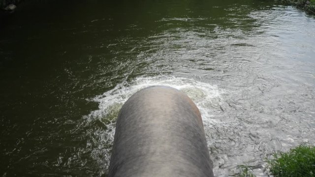 Large pipe spilling water into a pond.