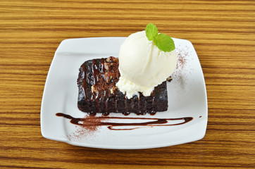 Chocolate brownie with ice cream and banana on white plate