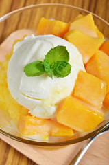 Ice cream scoop with fresh mango  in a glass dish.