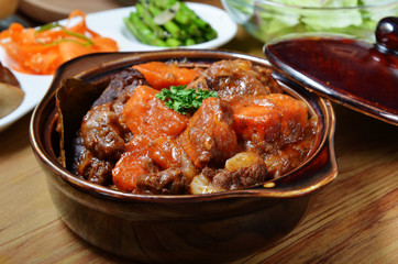 A bowl of beef stew on a wooden table 