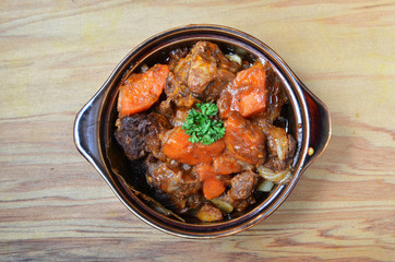 A bowl of beef stew on a wooden table 