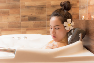 Obraz na płótnie Canvas Bathing woman relaxing in bath smiling relaxing. Multicultural Asian / Caucasian young woman in bathtub.