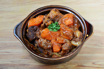 A bowl of beef stew on a wooden table 