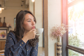 Beautiful cute girl in the cafe near the window with coffee