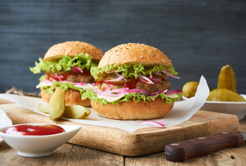 Hamburger with pickled cucumbers, onions, cheese, lettuce and tomato sauce