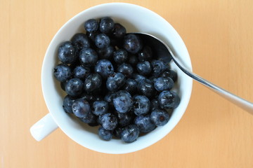 Blueberries in a white cup with a spoon. Top view.