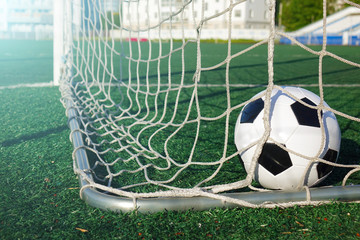Football on a green field. The ball in the goal.