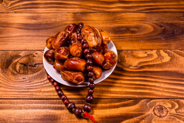 Date fruits and rosary on wooden table
