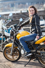 Fototapeta na wymiar Young woman biker sitting on her street bike and looking at camera