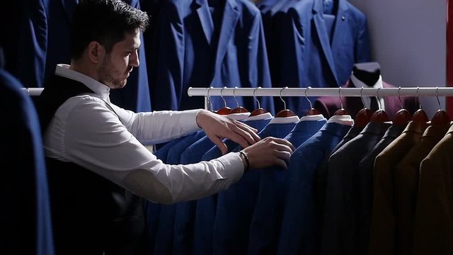Young man choosing classical suit in the suit shop