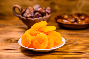 Dried apricots and date fruits on wooden table