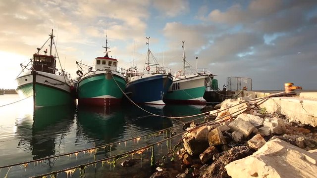 Beautiful medium shot footage of fishing boats moored in Gansbaai Harbor with a pretty sunset in the overberg region of south africa