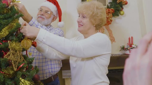 Happy old couple decorate Christmas tree together