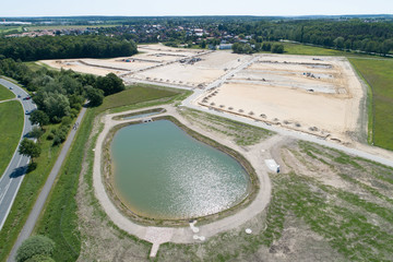 Aerial view from a rainwater Basin and anew development area on sandy ground with the planum for new houses, taken at an angle
