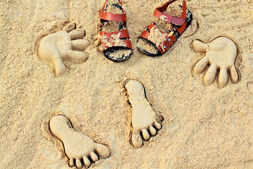 Sand on the beach or in the sandbox and footprints in the sand. Form for sand and children's shoes nearby. Can be used as a background image to copy space.