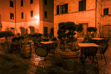 Old European narrow empty street of a medieval town at a foggy evening. Pienza, Italy