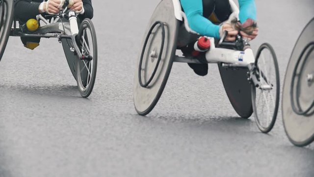 Marathon on the streets, disabled athletes in wheelchair racing on the background of the city, slow-motion