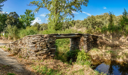 Fototapeta na wymiar Old antique stone bridge over stream