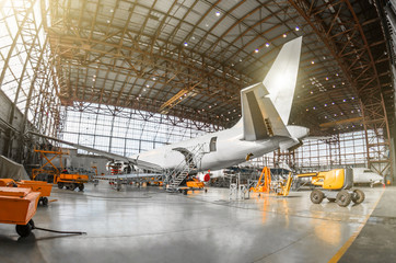 Large passenger aircraft on service in an aviation hangar rear view of the tail, on the auxiliary power unit. Mechanization of the tail is dismantled. - obrazy, fototapety, plakaty