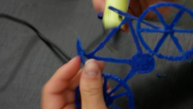 3D printing pen working by melting plastic to create a model of a bicycle.