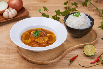 Tasty dinner with chicken curry in bowl on wooden background