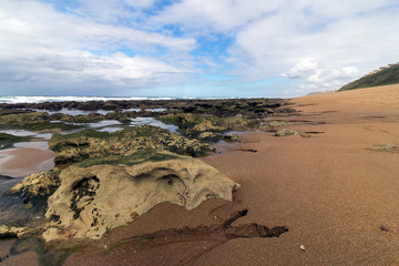 Rocky Beach Waves and Ocean Against Blue Cloudy Skyline