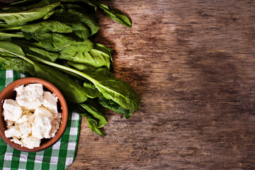 Fresh spinach and cheese on a wooden background.