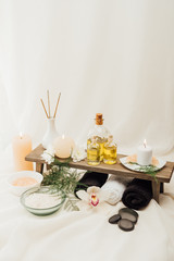 close up view of arrangement of spa treatment accessories with towels, oil and salt on white background