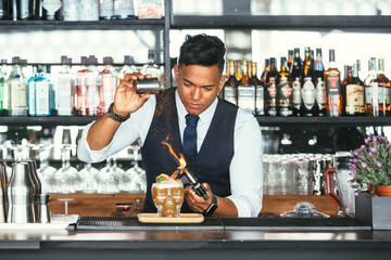 Expert barman uses a blowtorch for a cocktail