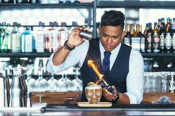 Expert barman using a blowtorch for a cocktail
