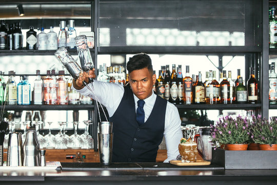 Expert bartender adds alcohol to a shaker