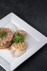 Buckwheat porridge with dietary meat on a white plate is tenderly served