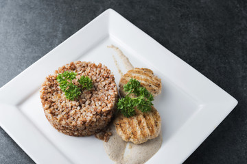 Buckwheat porridge with dietary meat on a white plate is tenderly served