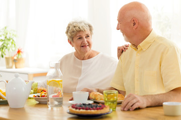 Smiling grandmother eating breakfast with husband in the morning