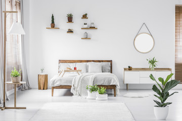 Morning in a bright and sunny modern white bedroom interior with wooden furniture. Cushions,...