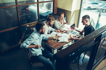 Young cheerful people smile and gesture while relaxing in pub.
