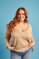 Casual plump woman with hands in pocket posing at the camera 