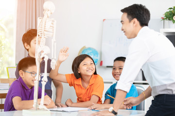 Asian teacher explains a human body structure to little pupil.