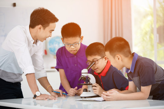 Asian boy examining preparation under the microscope