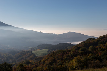 View of Umbria valley with hills full of autumn trees and Assisi